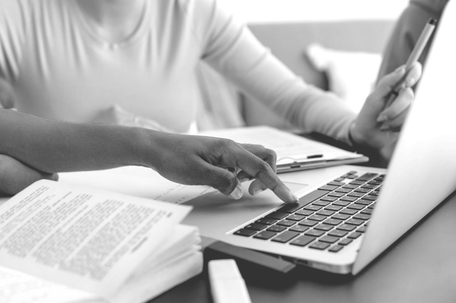 Person using calculator and notebook for budget planning at desk